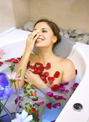 Obraz na płótnie Canvas happy woman in a bath with rose-petals