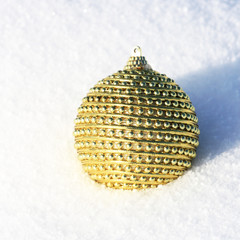 vergoldete Weihnachtskugel im Schnee