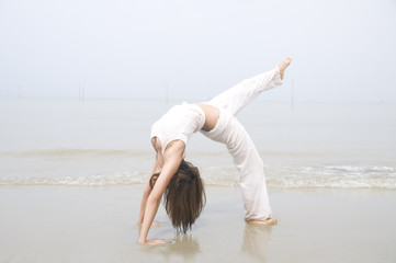 asian girl performing yoga on a beach