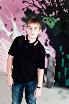 Young boy with shoulder bag agaisnt purple graffity wall