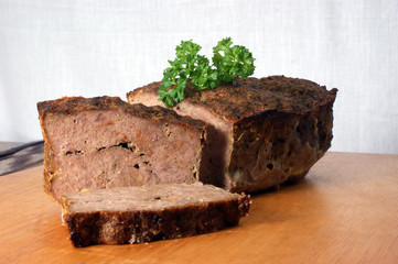 baked meat loaf with organic parsley on a timber board