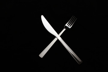 Kinfe and fork crossed on a black background