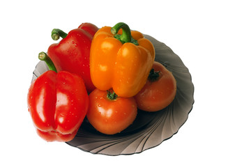 wet tomatoes and peppers at the plate on a white