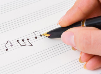 Hand with pen and music sheet