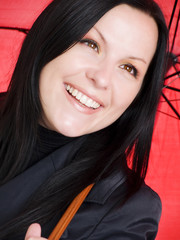 closeup of smiling brunette woman in fall clothes holding umbrel