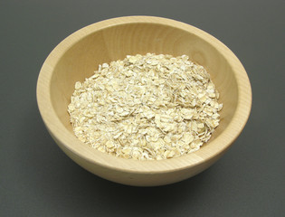 Holzschale mit Haferflocken auf matter Unterlage