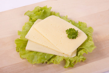 Cheese on wooden board with salad