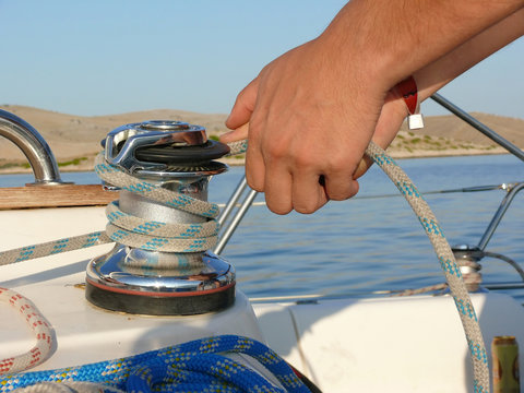 Sailor's hands and winch on a yacht