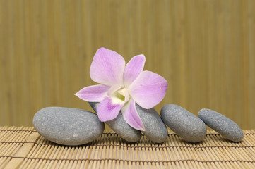 Fototapeta na wymiar pyramid of stones with purple orchids, Spa essentials