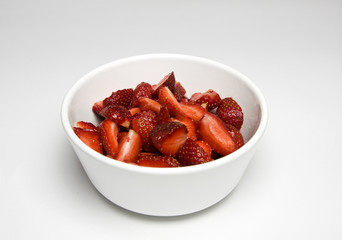 Some sliced strawberries in white bowl