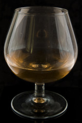 Glass of brandy on black background