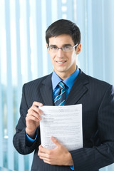 Happy businessman with documents at office