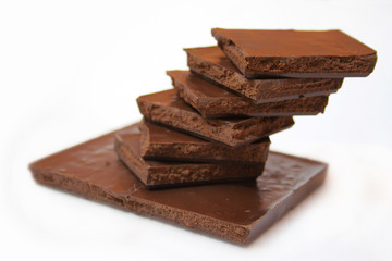 Delicious pieces of dark chocolate or milk chocolate stacked on a white background