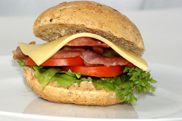 bacon burger on a plate with tomato and cheese