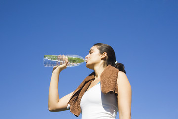 Young sexy woman drinking water after exercise