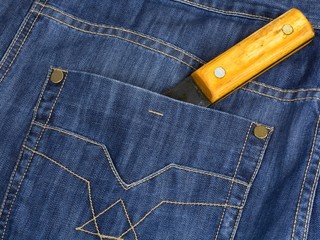 The hatchet handle is shown from a pocket jeans