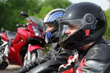 Fototapeta na wymiar closeup of two motorcyclists sitting on country road near bikes