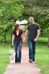 Obraz premium Happy Young Couple Walking the Dog