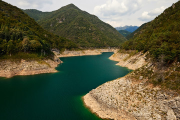An artificial lake in mountains with low water level.
