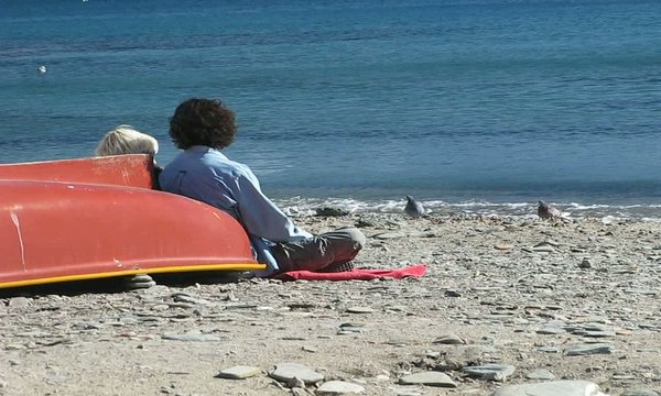PAREJA TOMANDO EL SOL EN LA ORILLA DEL MAR