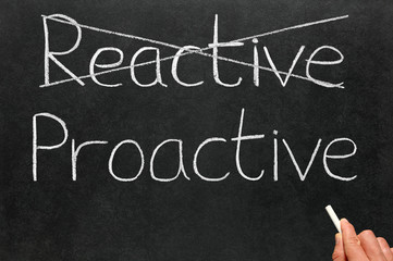 Crossing out reactive and writing proactive on a blackboard.