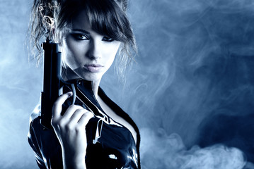 beautiful sexy girl holding gun . smoke background - obrazy, fototapety, plakaty