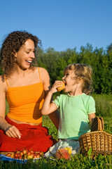 pretty Little Girl and Young Women eats fruits on picnic