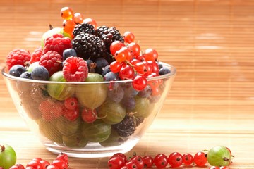 Fruit mix in the glass container, on a table from straw