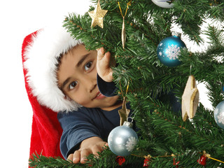 child hiding behind the christmas tree