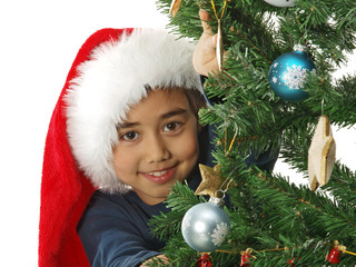 child hiding behind the christmas tree