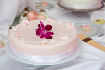 Wedding cake with pink icing decorated with an orchid flower