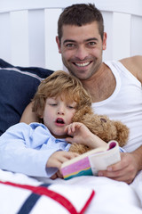 Obraz premium Father and son reading a book in bed