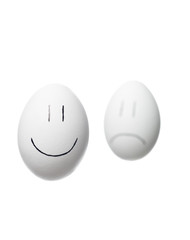 Sad face out of focus and a happy face painted on white eggs