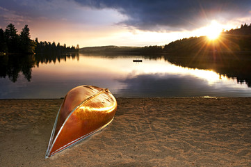 Lake sunset with canoe on beach