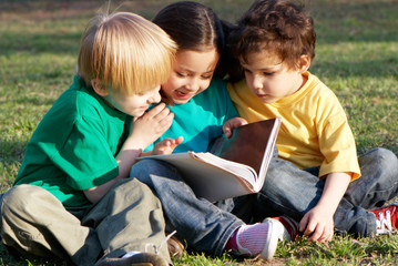Fototapeta premium Group of children with the book on a grass in park