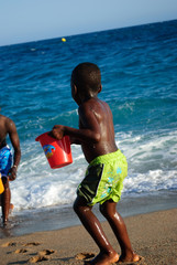 Enfant jouant à la plage avec un seau d'eau