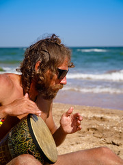 Man drum on tam-tam on the beach