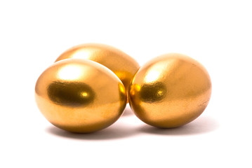 Three golden eggs on studio white background