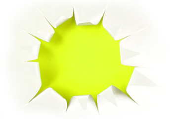 Hole ripped in white paper on green or yellow background. Copy space