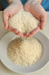 Two hands with rice grains over plate