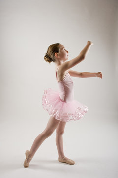 young girl practicing ballet dressed in pink tutu