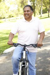 Obraz premium Senior Man Riding Bike In Park