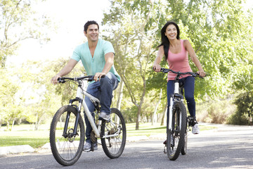 Obraz premium Young Couple Riding Bike In Park