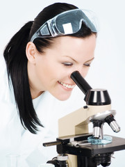smiling female researcher working on microscope in laboratory