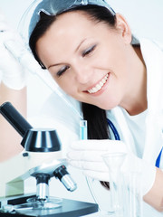 smiling female researcher holding test tube in laboratory