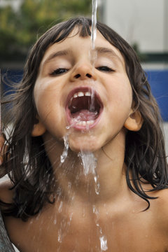 little girl drinking from a water fountain..
