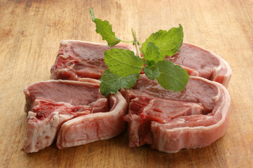 organic raw lamb chops on a timber board