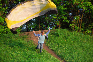 boy with parachute running from hill