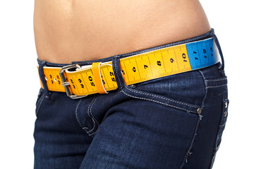 Closeup photo of a slim woman's abdomen and jeans with measuring