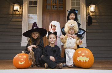 Children in Halloween costumes with pumpkins